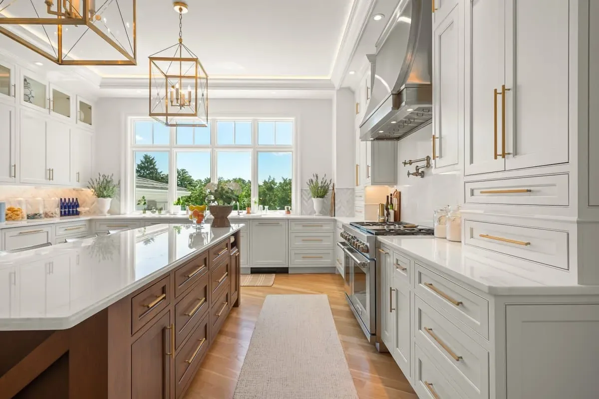 White kitchen with a walnut island and brass lantern pendants in a Norman Builders custom home, Andover MA