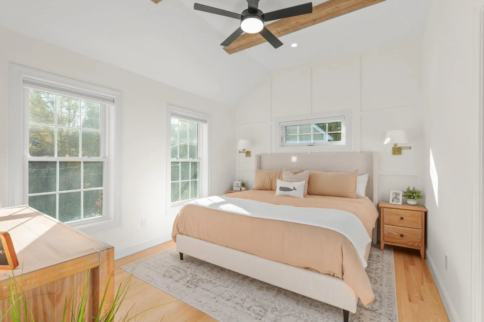 Vaulted primary bedroom with reclaimed wood beams and wall panel moulding