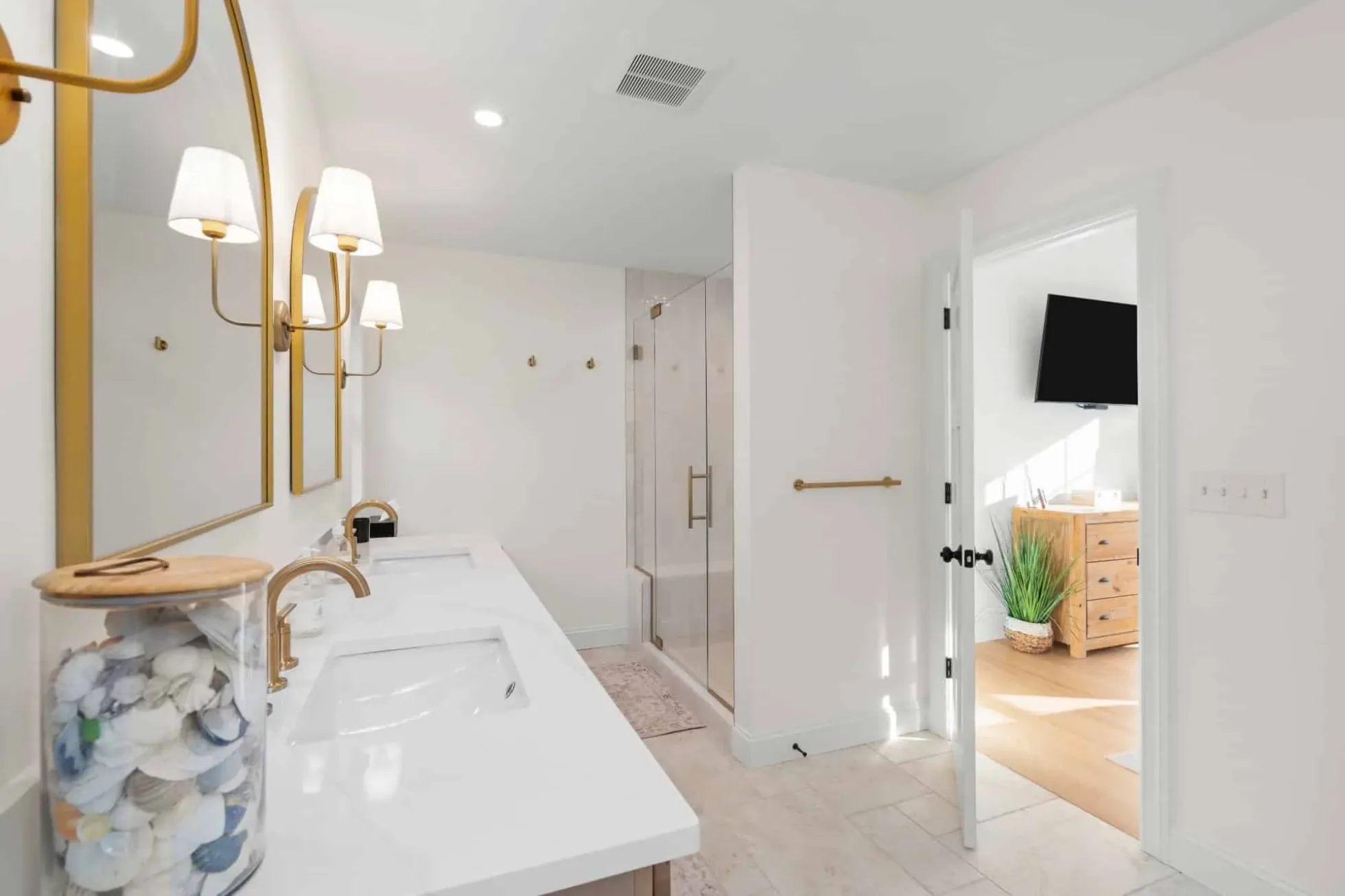 Vanity and doorway from the primary bath into the bedroom with hardwood floors