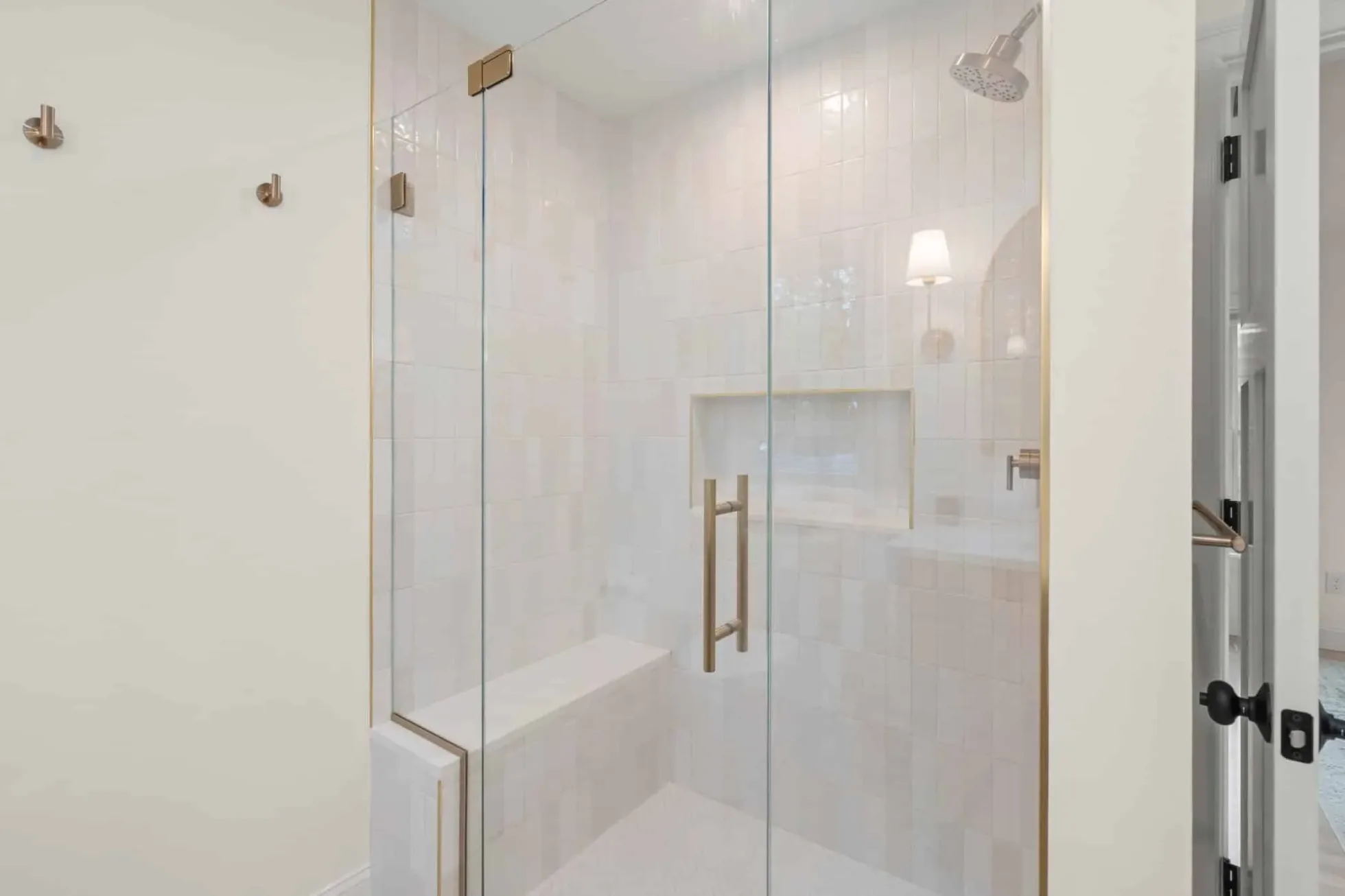 Walk-in shower with frameless glass, a built-in bench and full-height tile