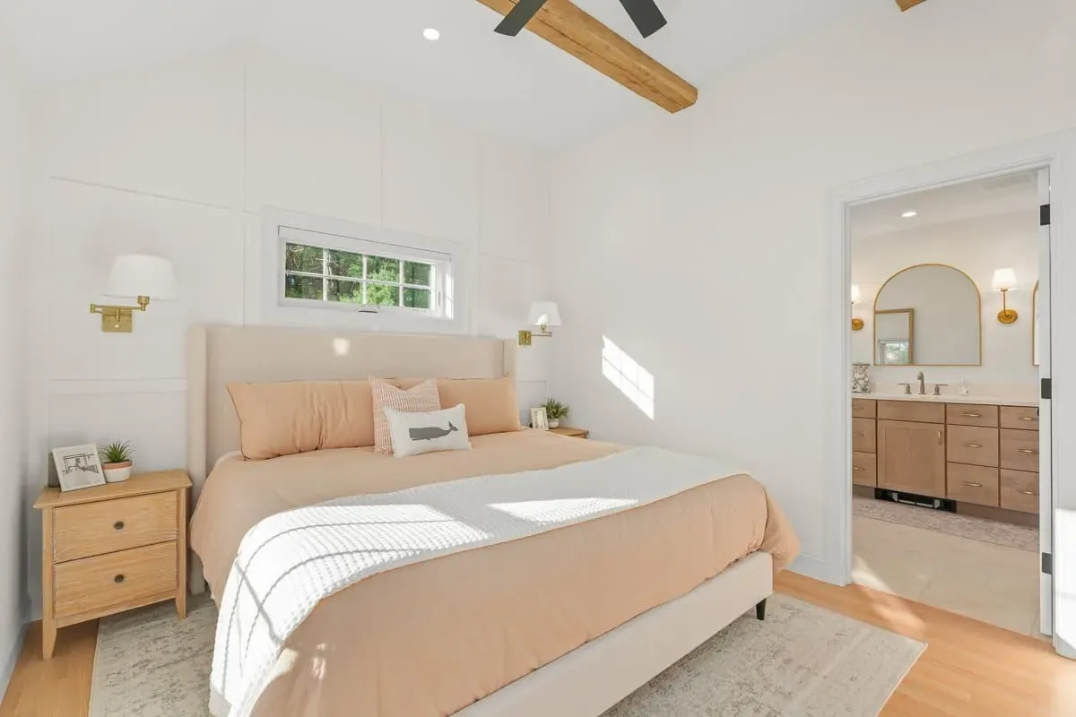 Primary bedroom looking through to the bath, with exposed beams and a ceiling fan