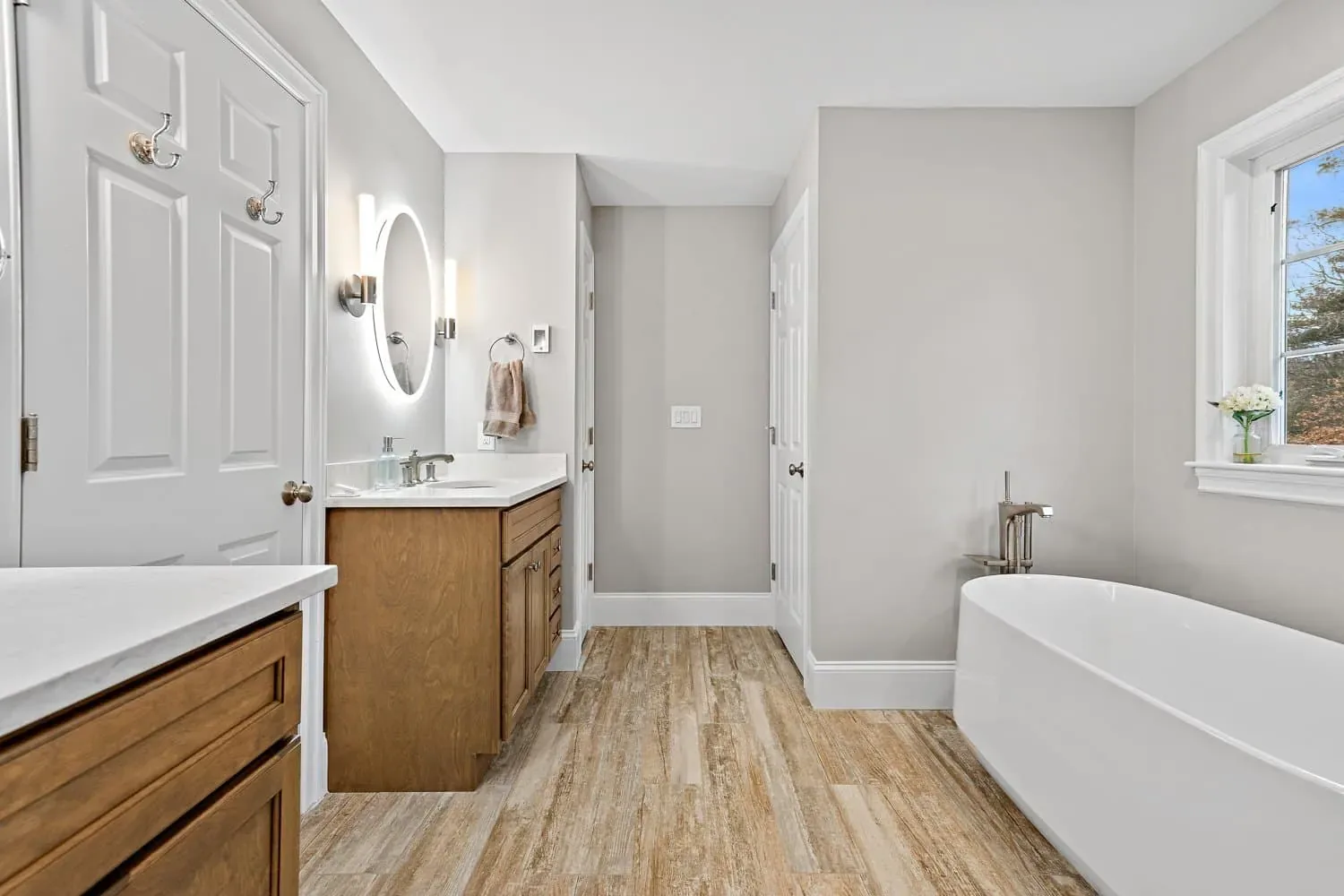 Dual custom maple vanities on opposite walls with the tub beyond
