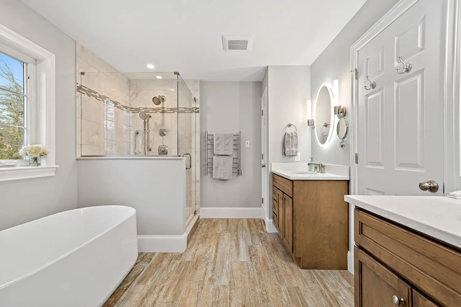 Primary bath with the tub, glass shower and one of two maple vanities