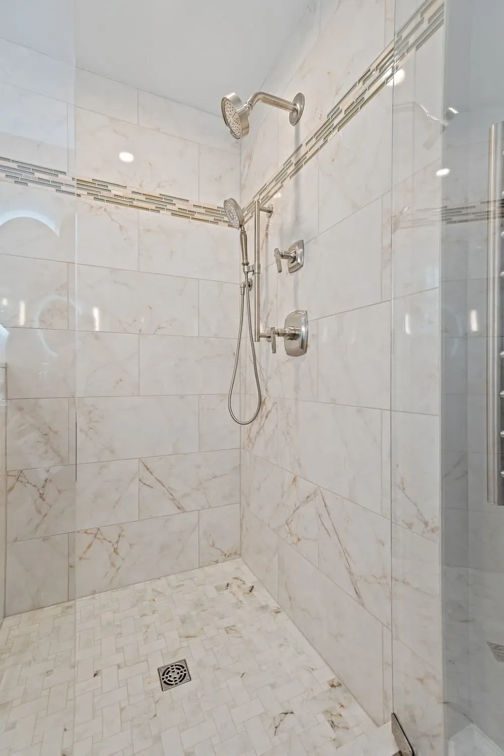 Frameless glass shower with porcelain mosaic floor and accent band