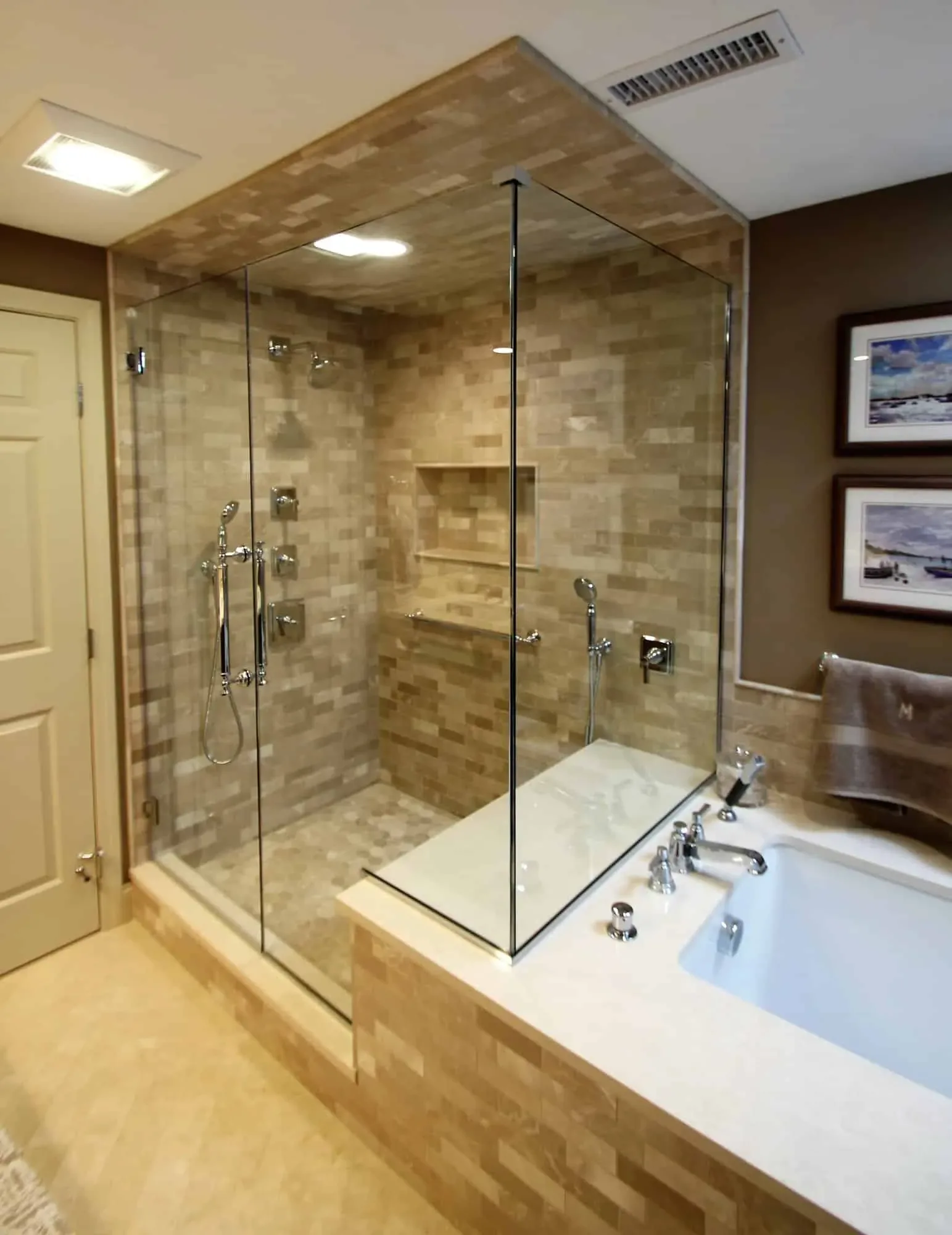 Frameless glass shower enclosure beside a stone-surround soaking tub, Byfield MA