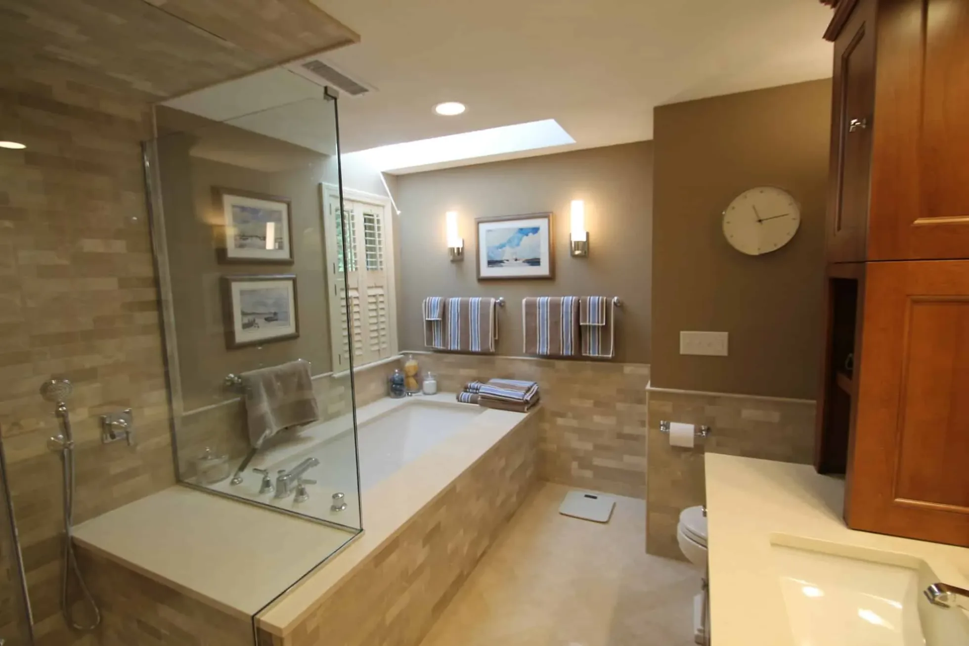 Stone-tiled primary bath with a frameless glass shower, soaking tub and skylight, Byfield MA