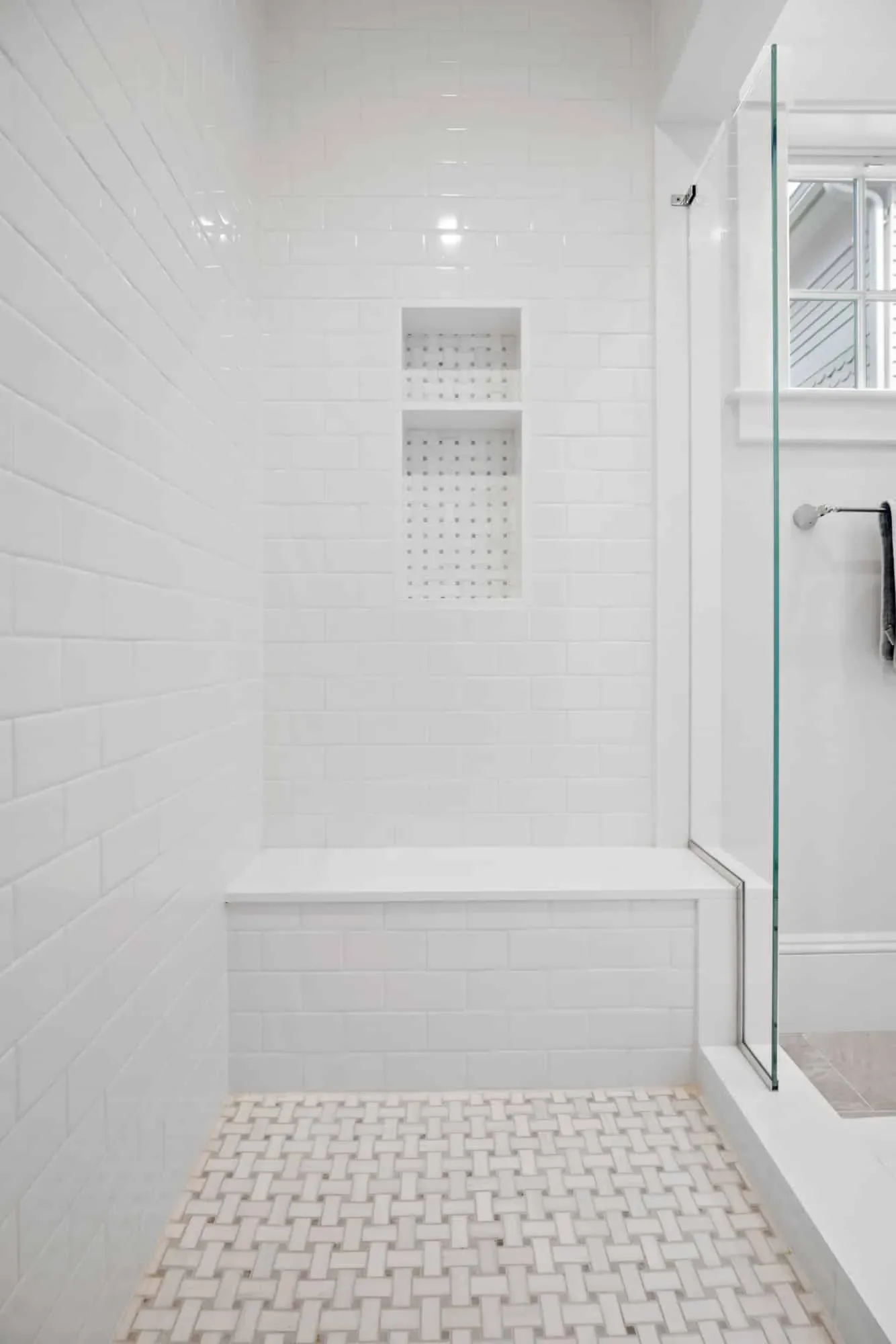 Walk-in shower with a built-in bench, niche and basketweave mosaic floor