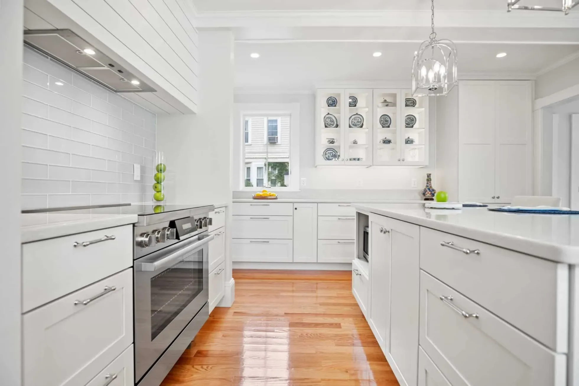 White shaker cabinets and quartz counters along the range wall, hardwood floors