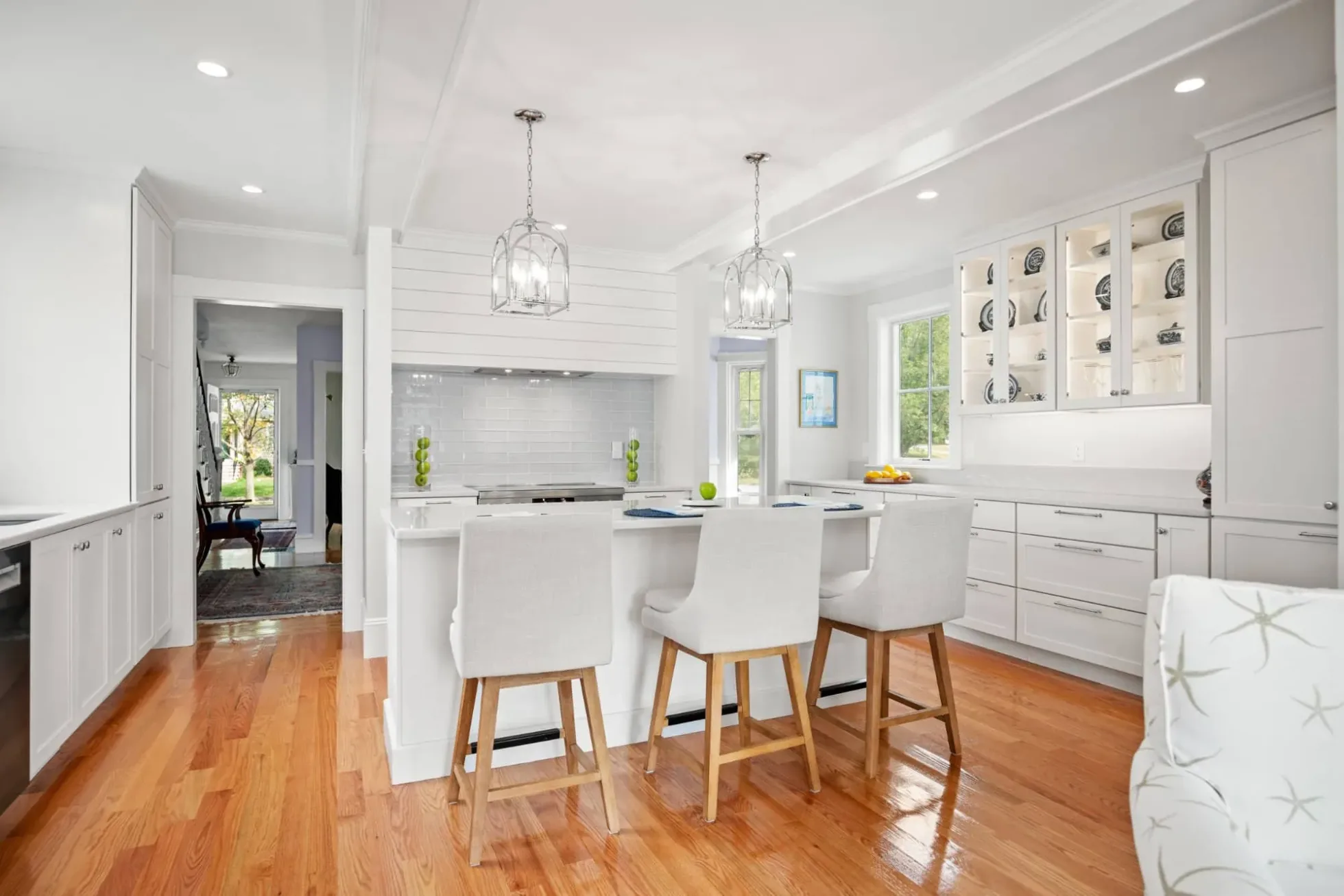 Bright white kitchen with a seating island, lantern pendants and glass display cabinets, Andover MA addition