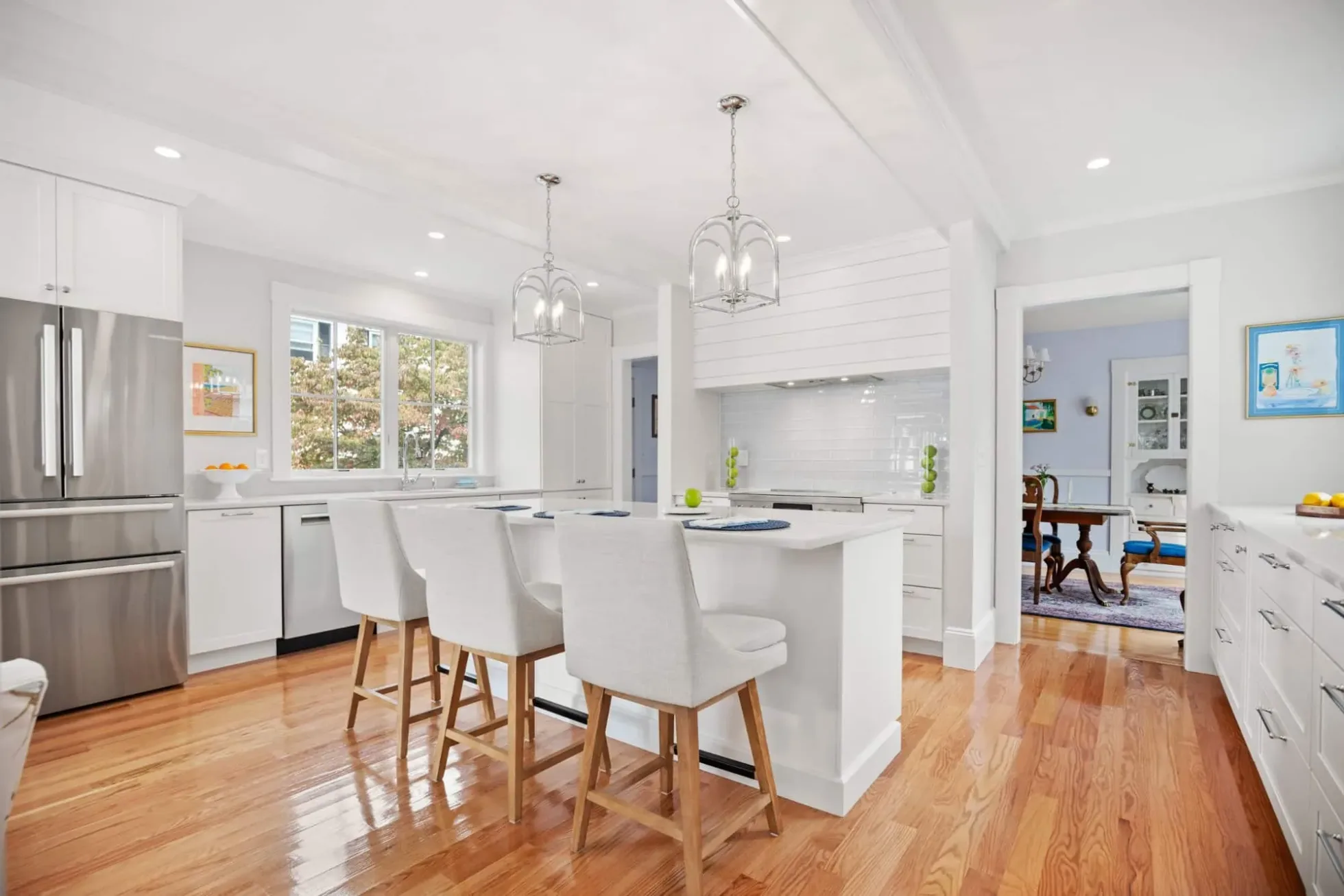 Island with four stools facing the stainless refrigerator and windows