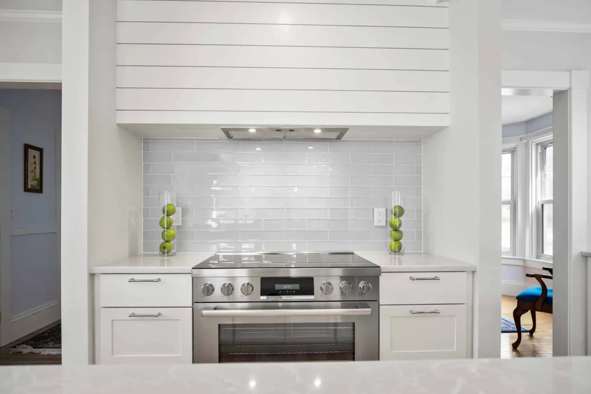 Range wall with gloss subway tile and a shiplap hood, dining room beyond