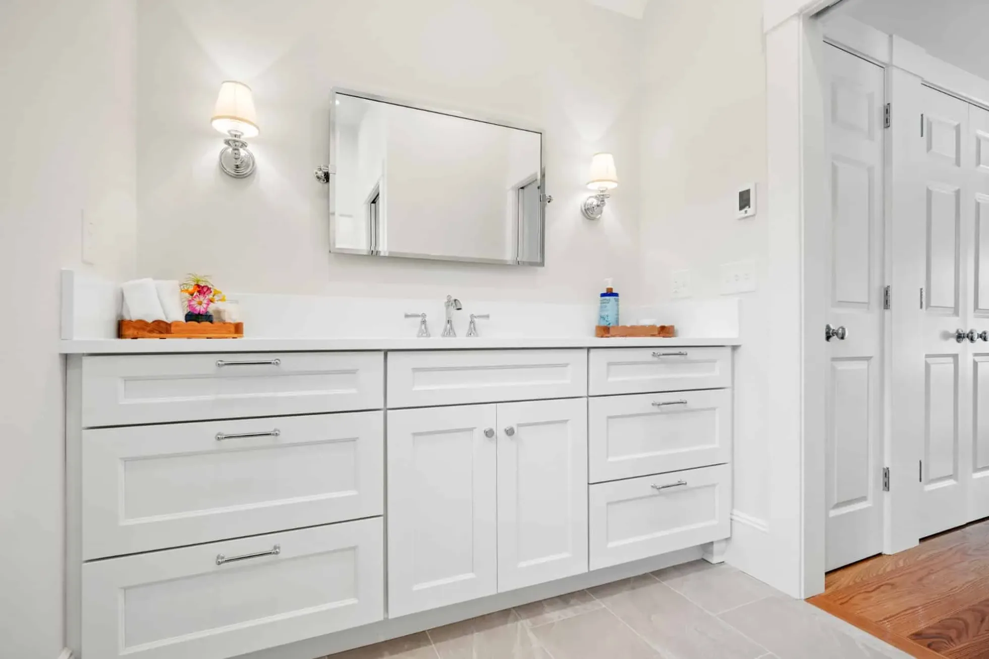 Primary bath with a white shaker vanity, quartz top and polished chrome sconces