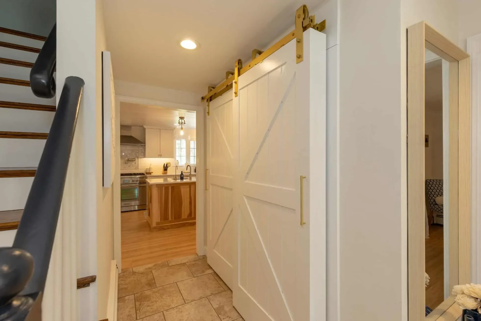 Painted barn door with brass hardware in a hallway leading to the kitchen