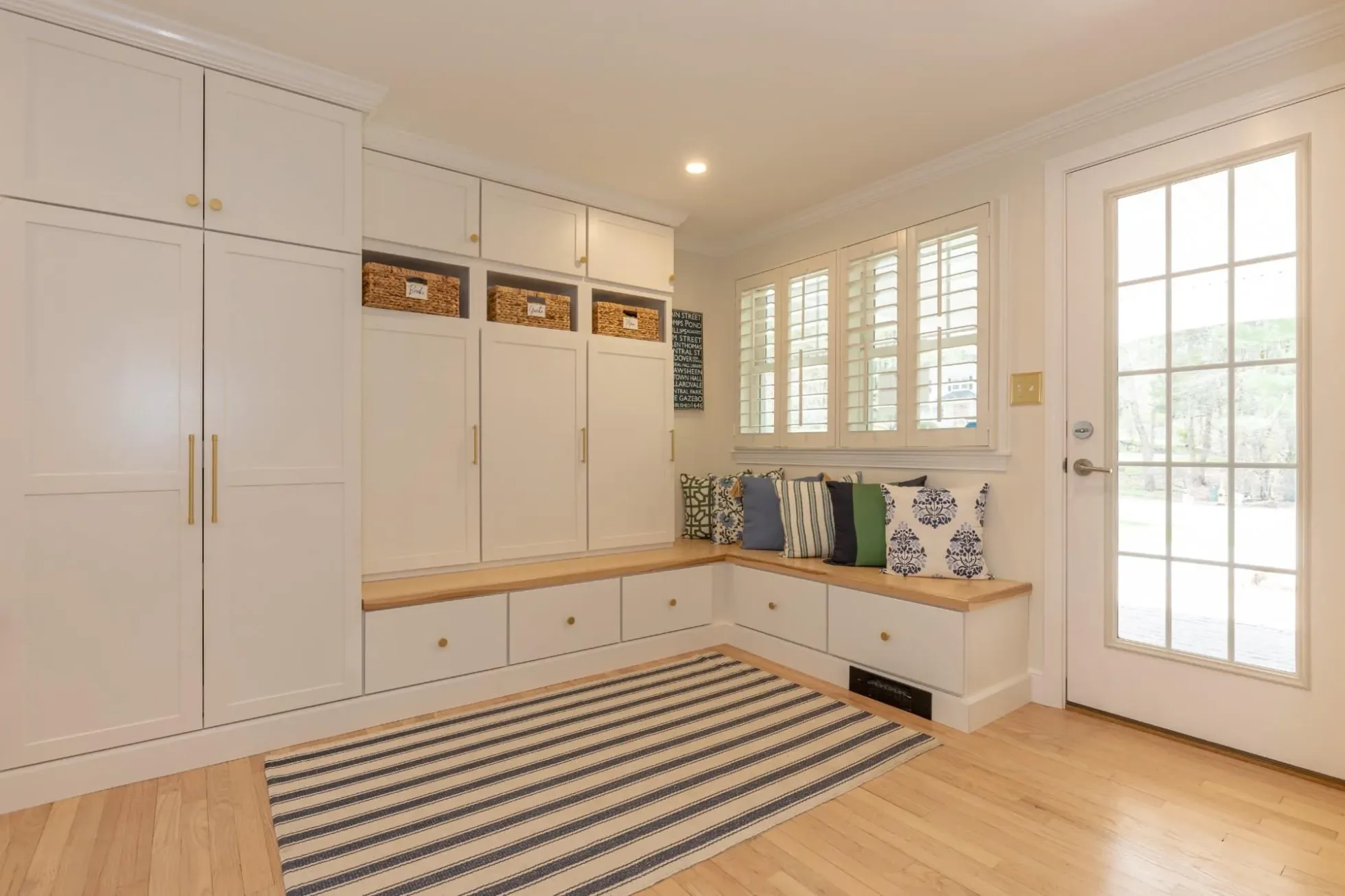 Mudroom with tall built-in cabinets, cubbies and a window seat bench