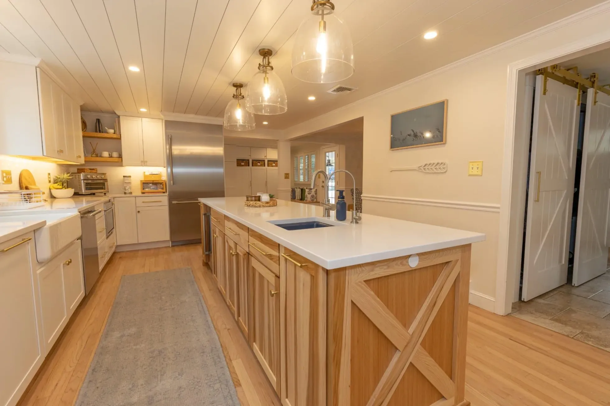 Sink in the white oak island facing the farmhouse sink wall and display shelving