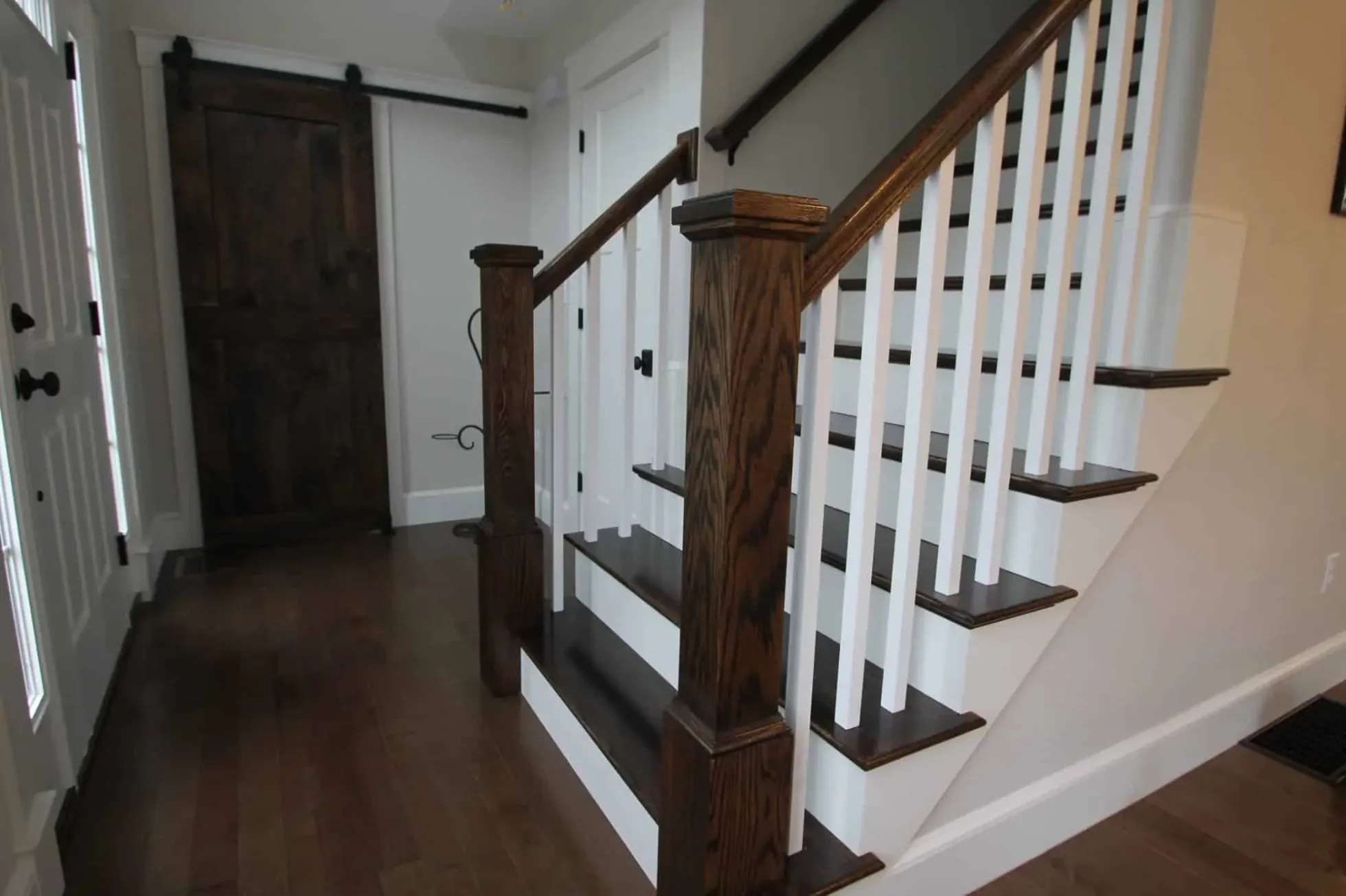 Stained hardwood stair treads and rails with painted balusters beside a sliding barn door, Groveland MA