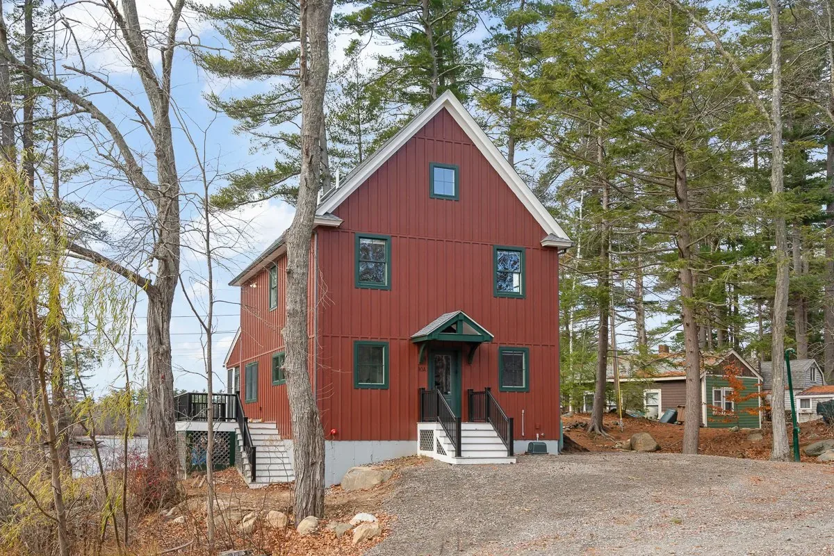 Front of the red cottage with a covered entry and stone-lined drive