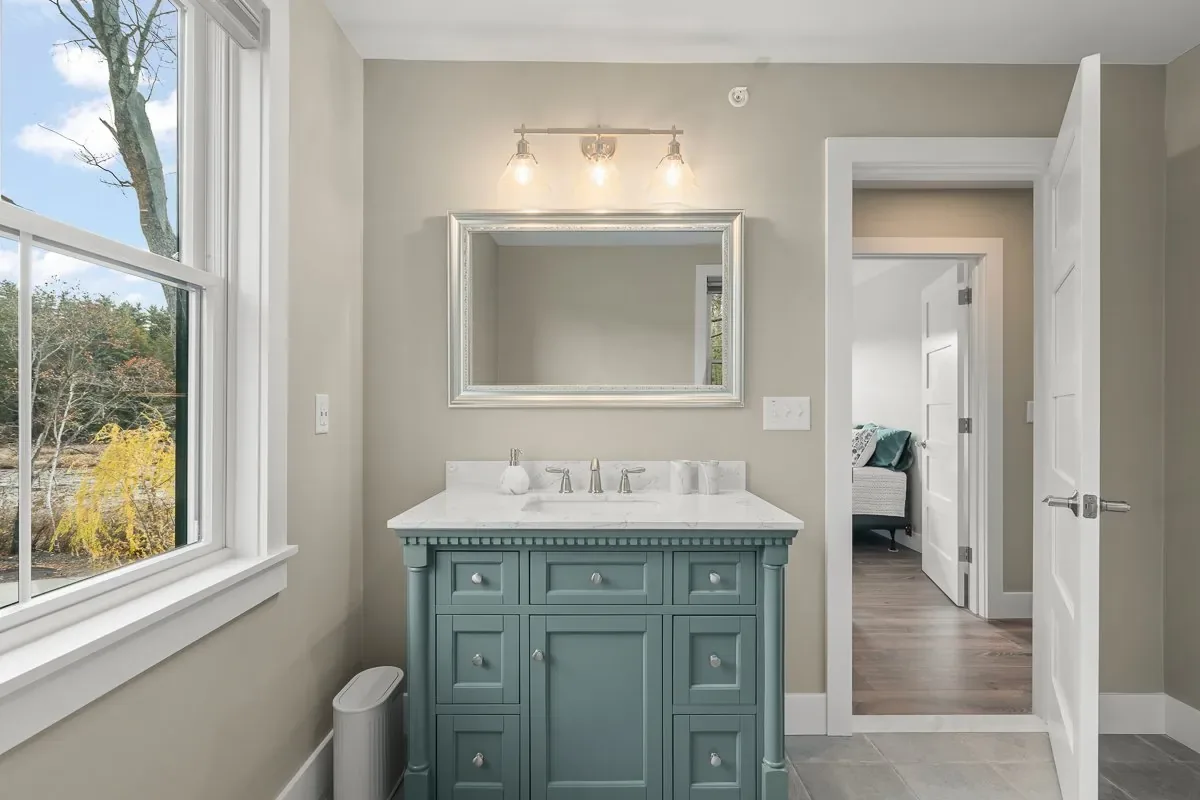 Painted vanity with a quartz top and brushed nickel fixtures beside a window