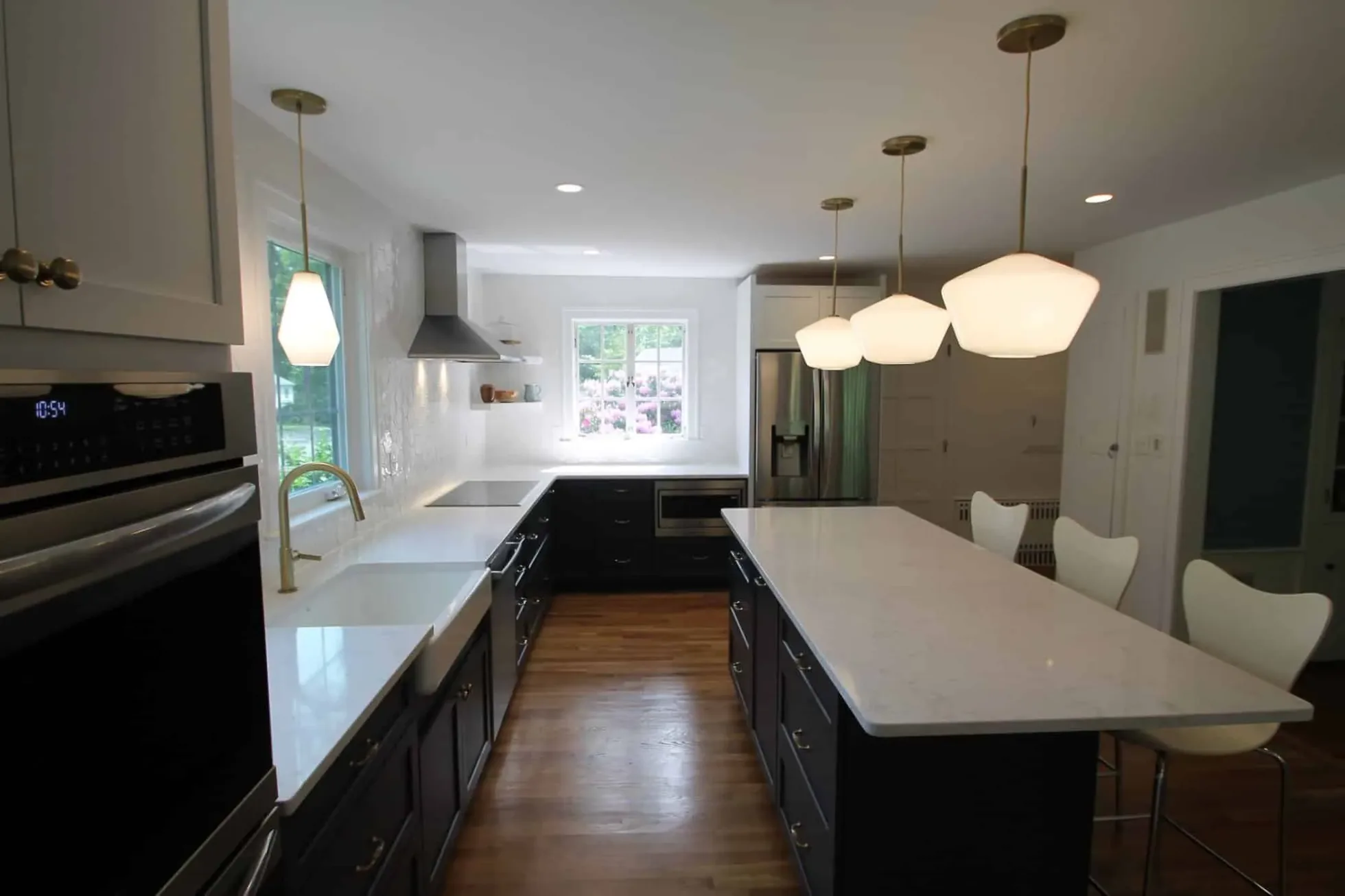 Long view along the island toward the windows, dark lower cabinets and white uppers