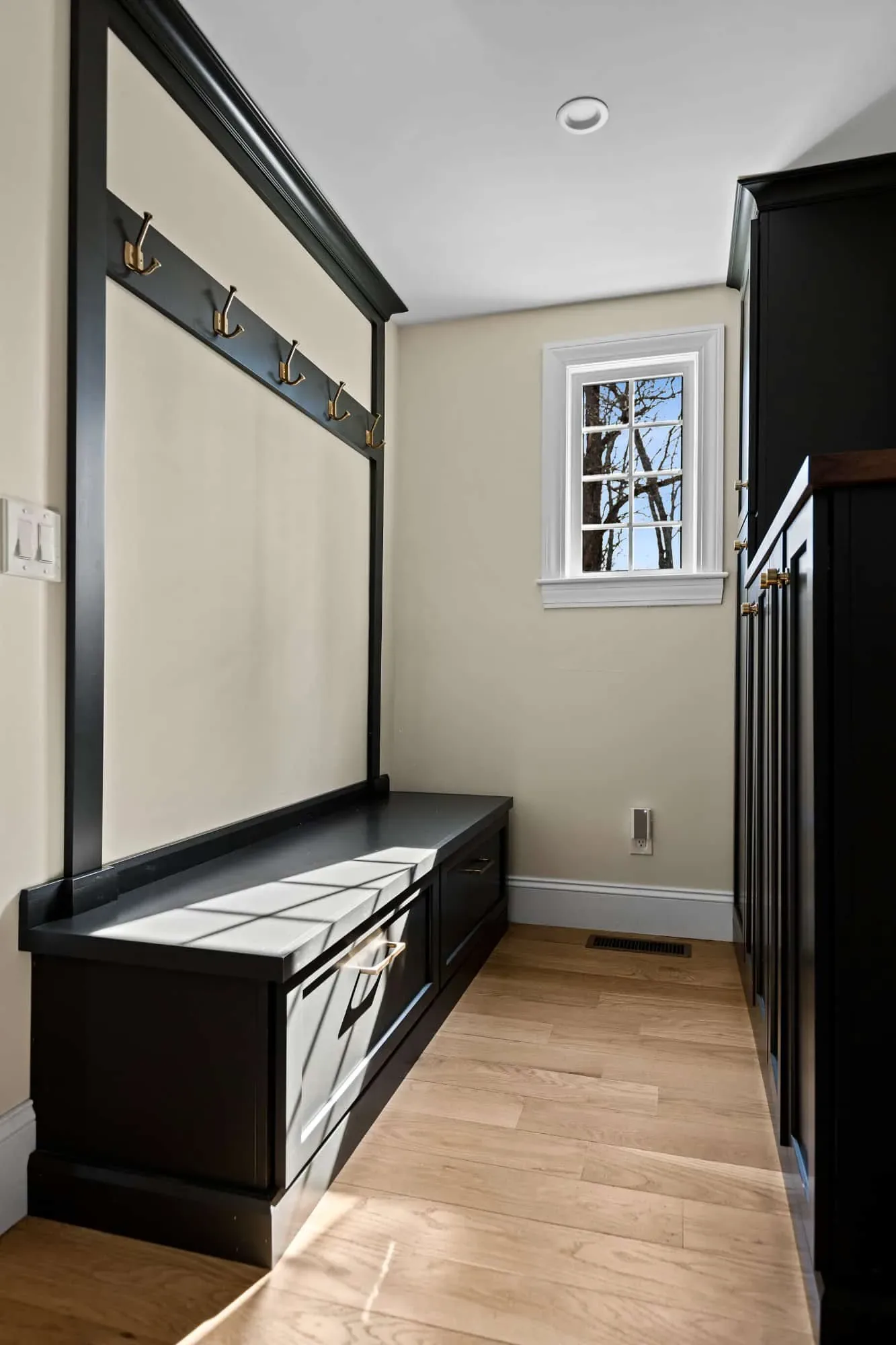 Mudroom bench and coat hooks under a window