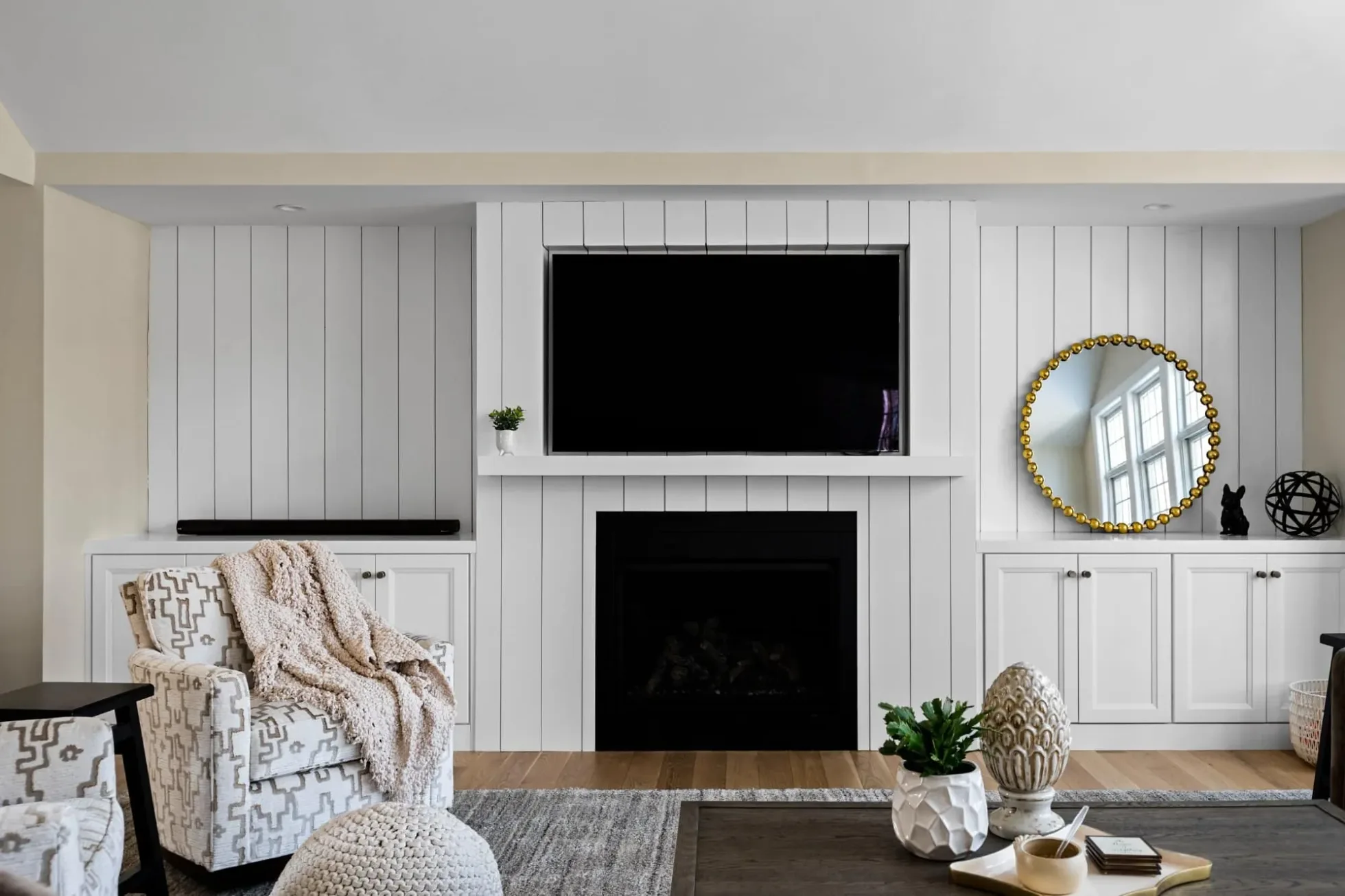 Family room fireplace wall with shiplap, built-in cabinets and a mounted TV