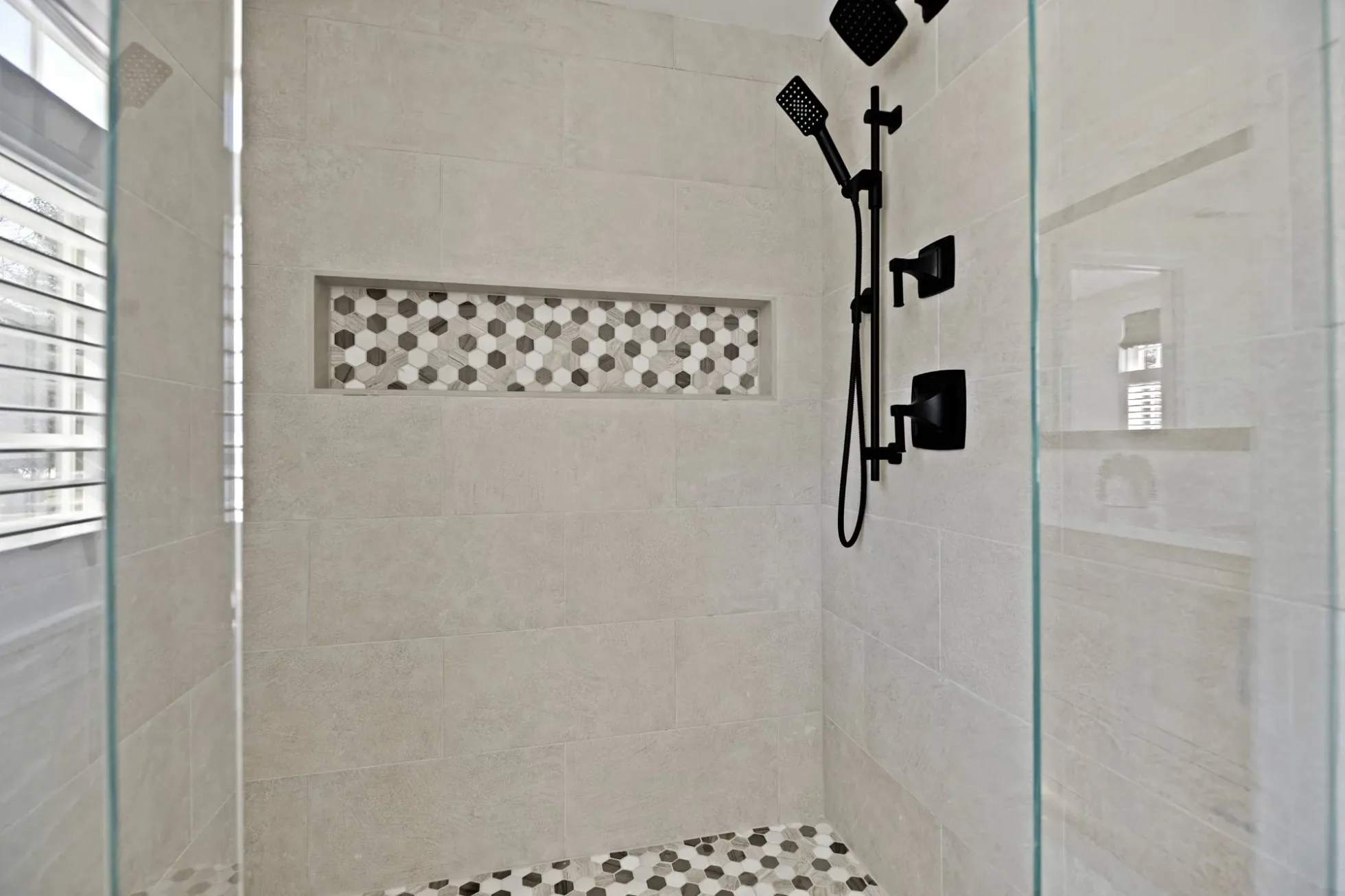 Walk-in shower with large-format tile, a mosaic niche and matte black fixtures