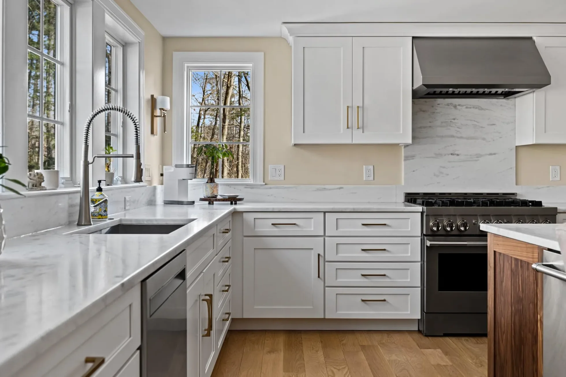 Sink run under windows with a full-height marble-look backsplash and range hood