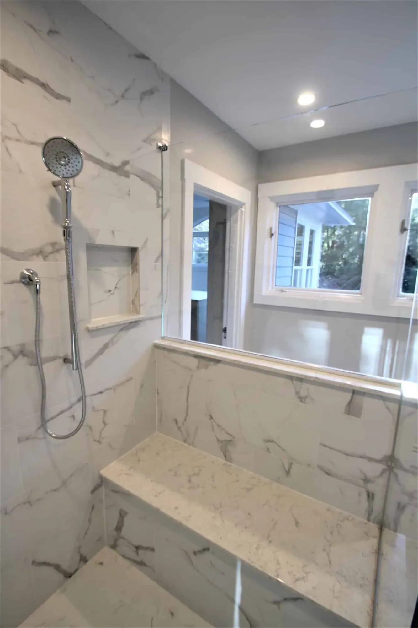 Shower bench and recessed niche in floor-to-ceiling marble-look porcelain tile