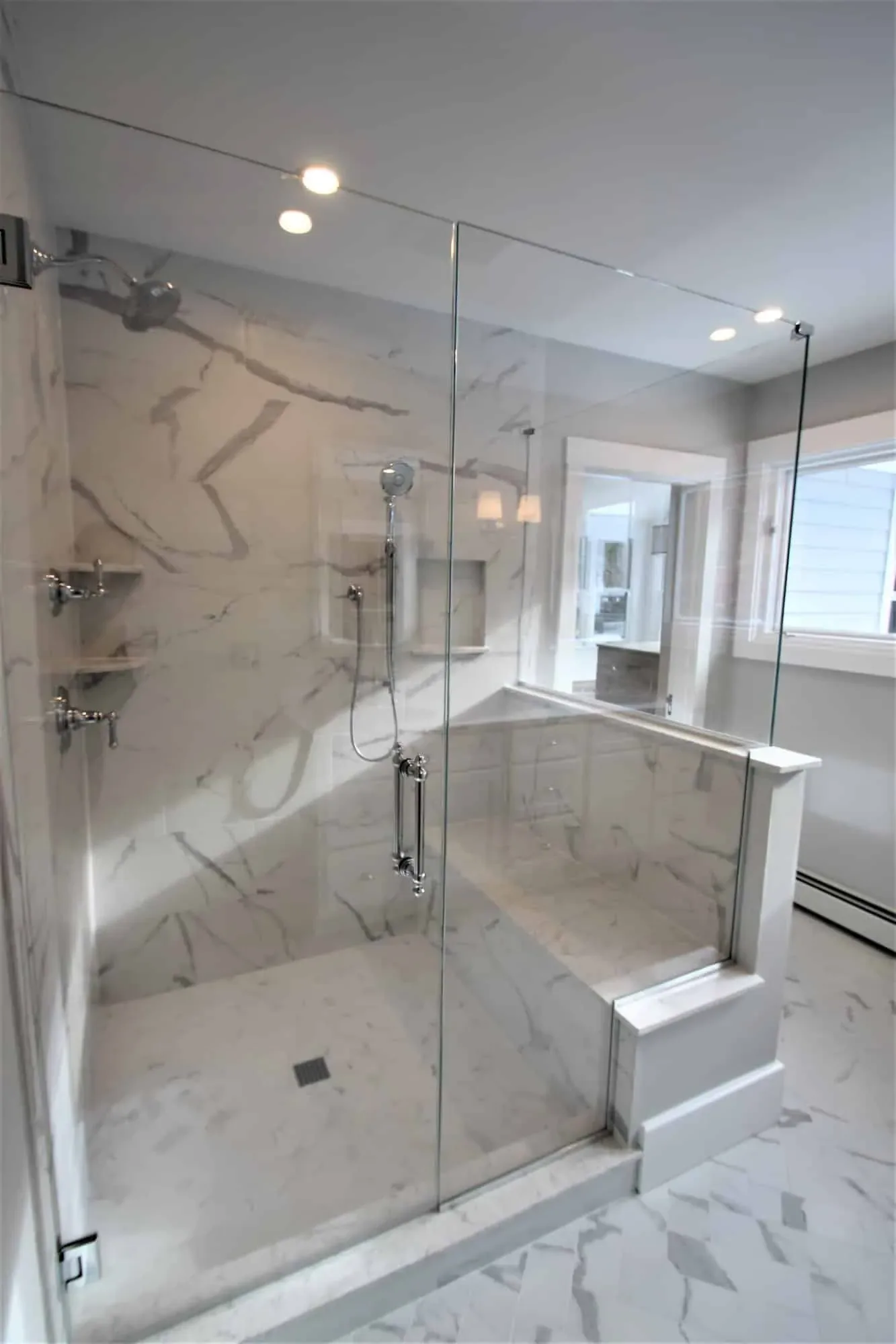 Frameless tempered glass shower enclosure with a handheld shower system