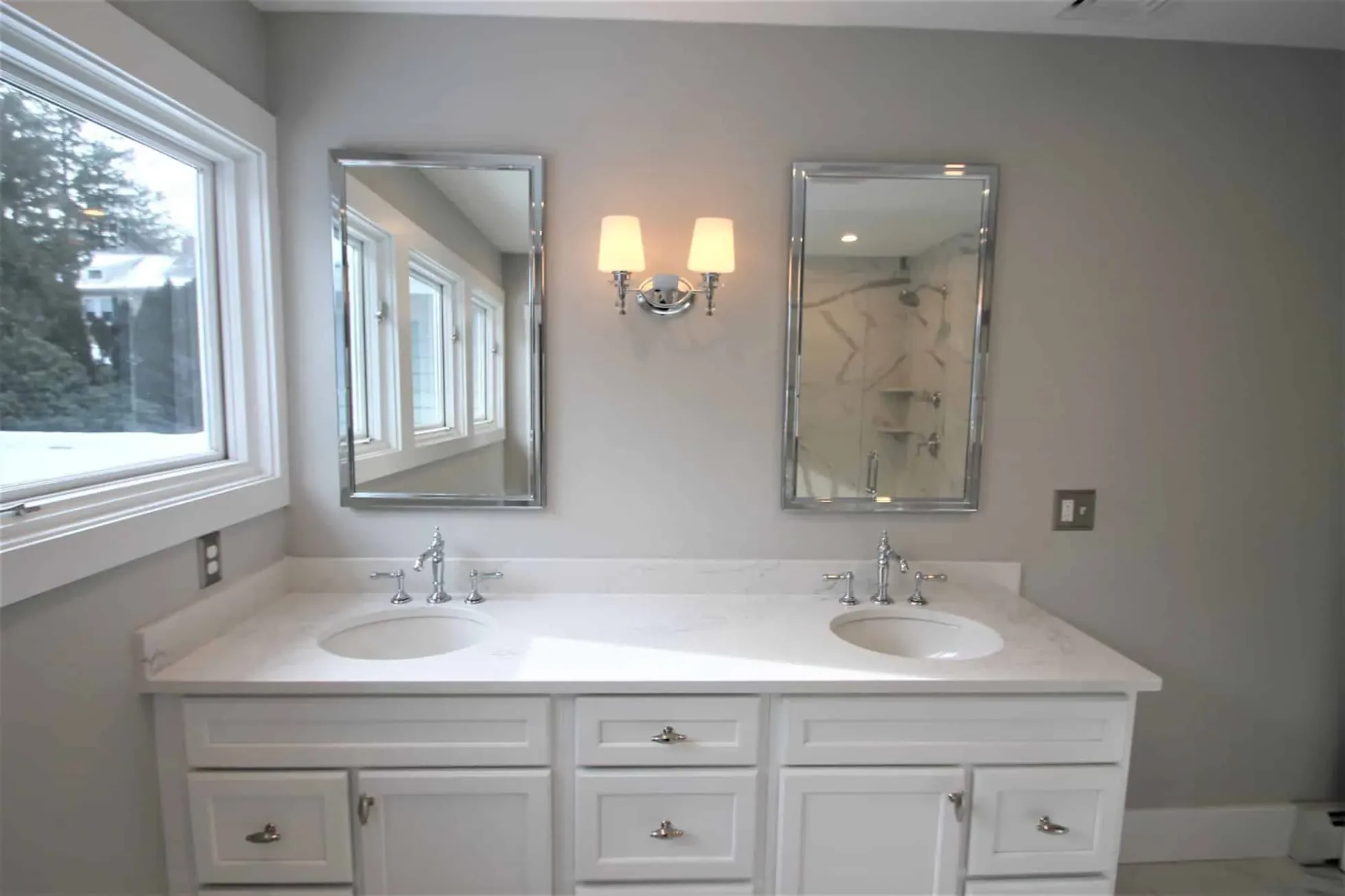 White painted shaker double vanity with framed mirrors and chrome sconces beside a large window, Andover MA primary bath