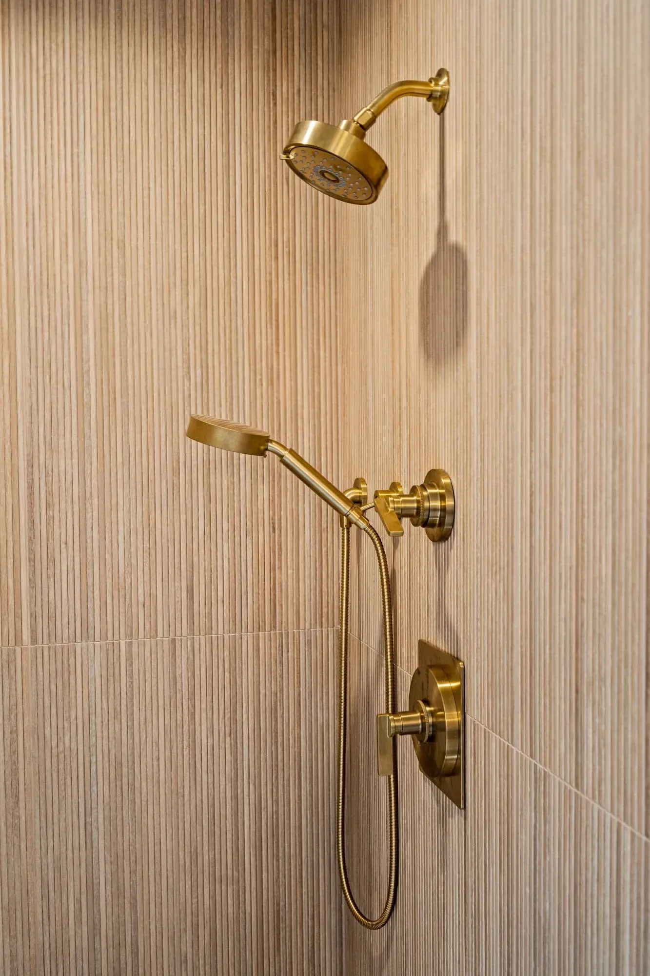 Brushed brass rain head and handheld shower on textured porcelain