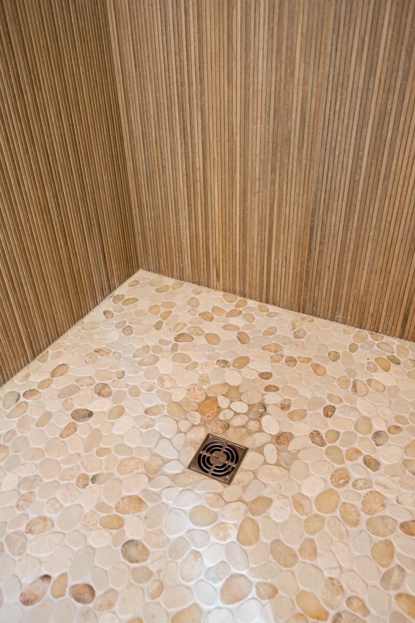 Pebble-style shower floor tile with a brass drain