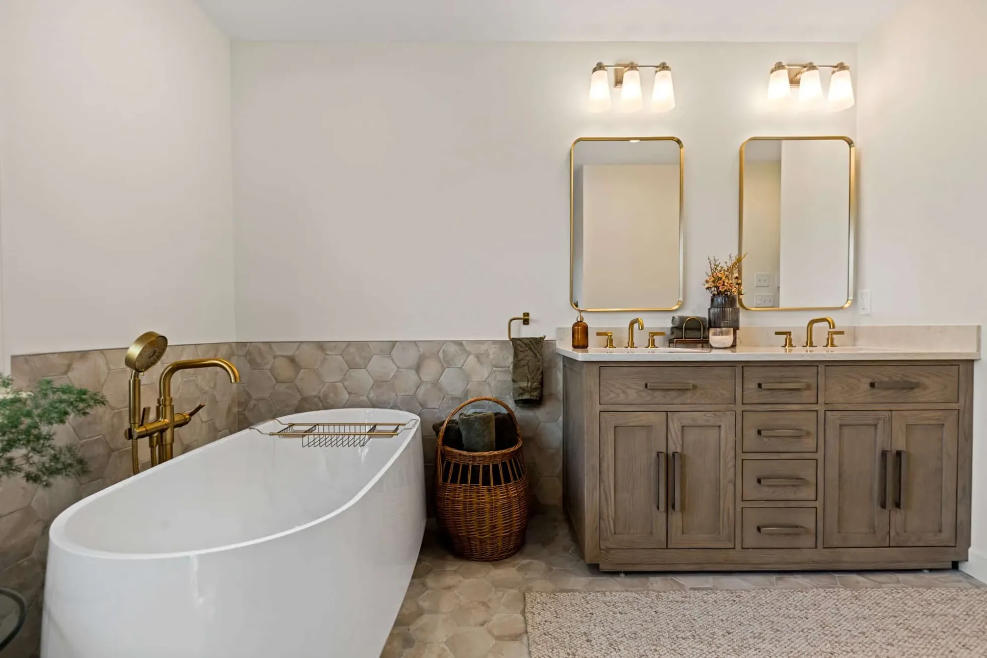 Freestanding soaking tub beside a white oak double vanity with brushed brass mirrors, Andover MA primary bath