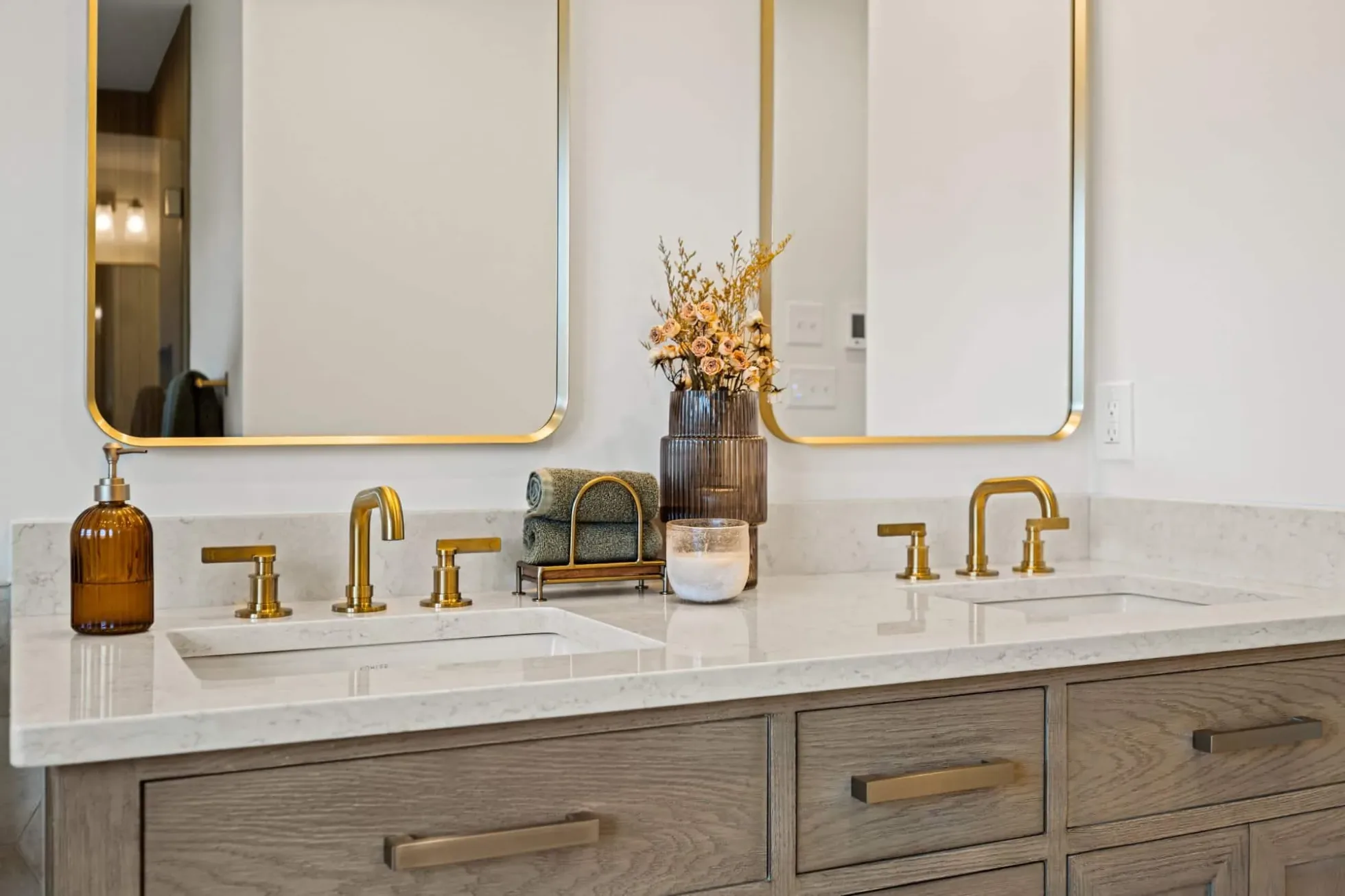 White oak double vanity with white quartz top, brass faucets and brass-framed mirrors