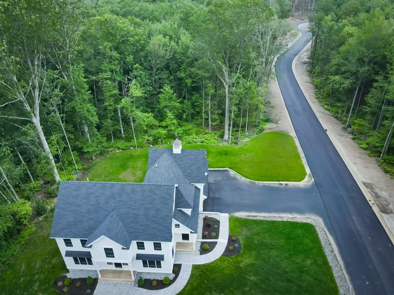 Aerial view of the home, driveway and lawn on a wooded lot, Newton NH