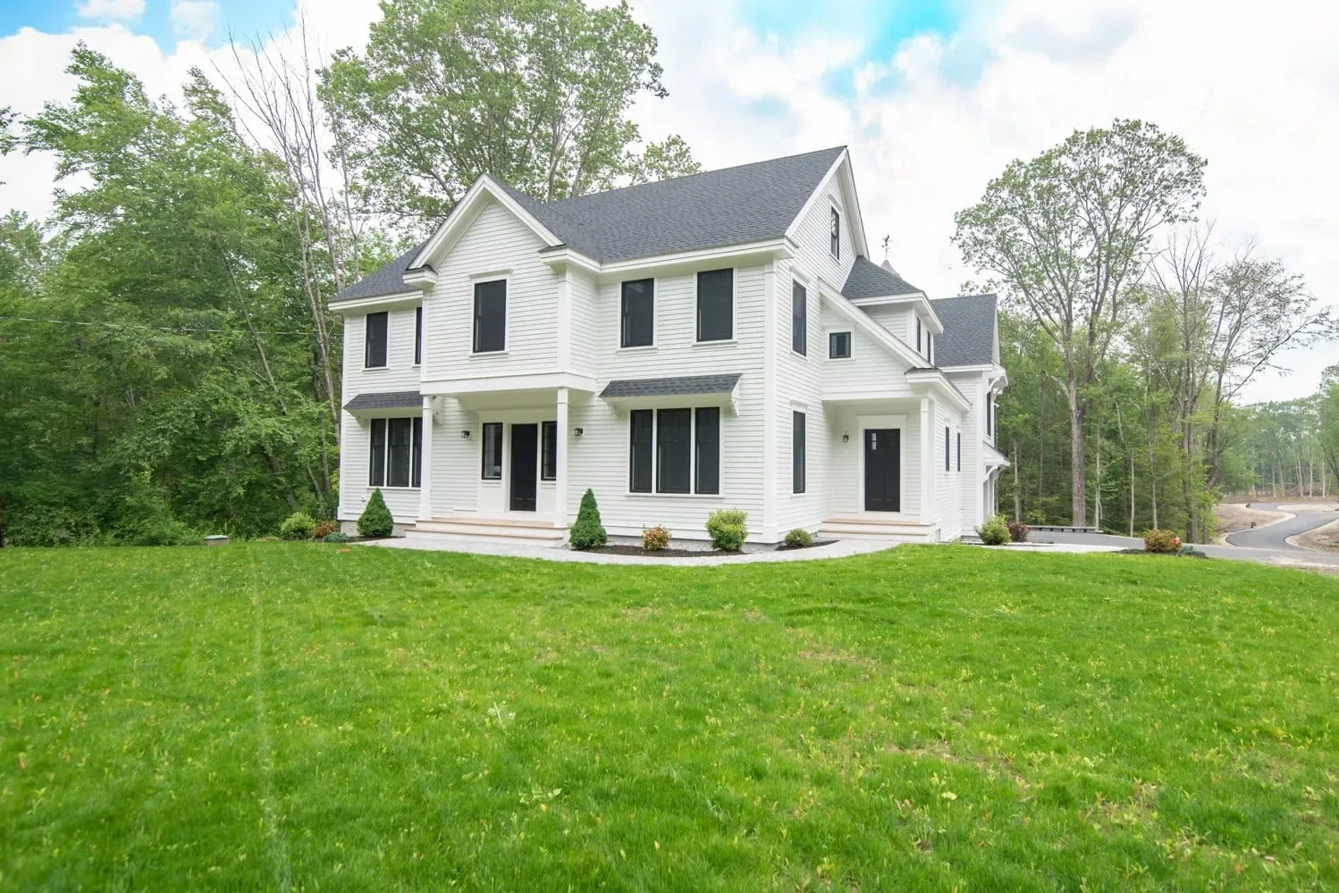 Front of the White Cedar Way home with a covered porch and landscaped lawn, Newton NH