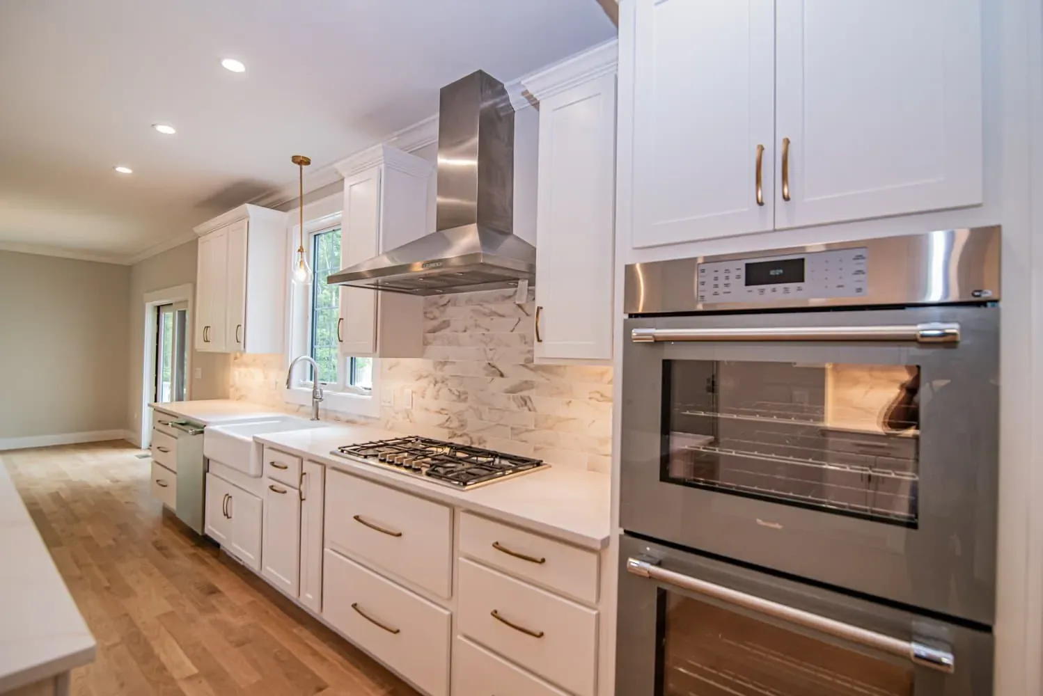 Gas cooktop with a stainless chimney hood and marble-look backsplash, Newton NH kitchen