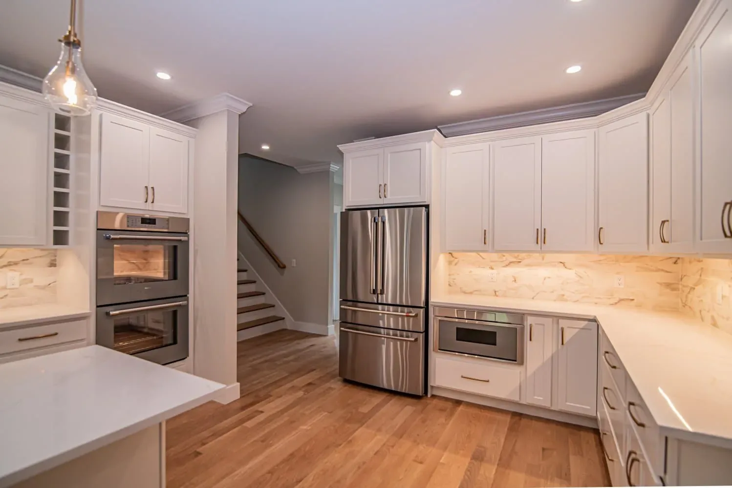 Kitchen with double wall ovens and a stainless refrigerator beside the stairs, Newton NH