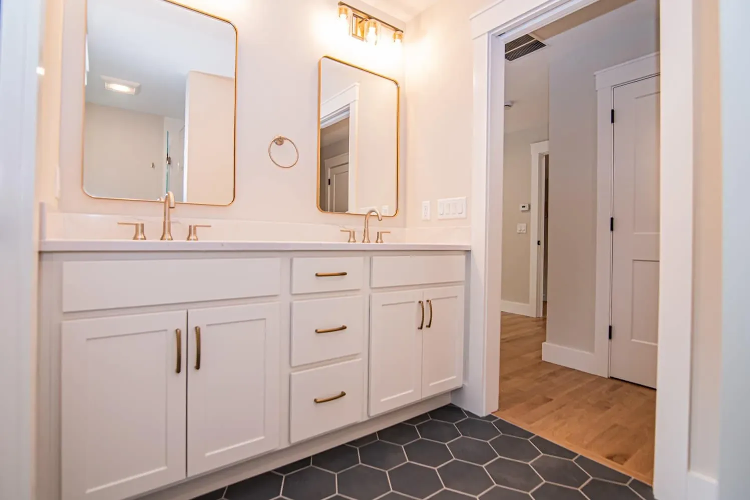 Double vanity with brass fixtures and arched mirrors in the primary bath, Newton NH