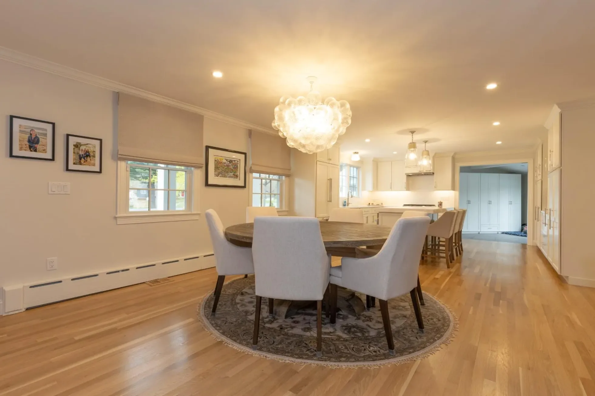 Dining room with a round table and statement chandelier, kitchen beyond