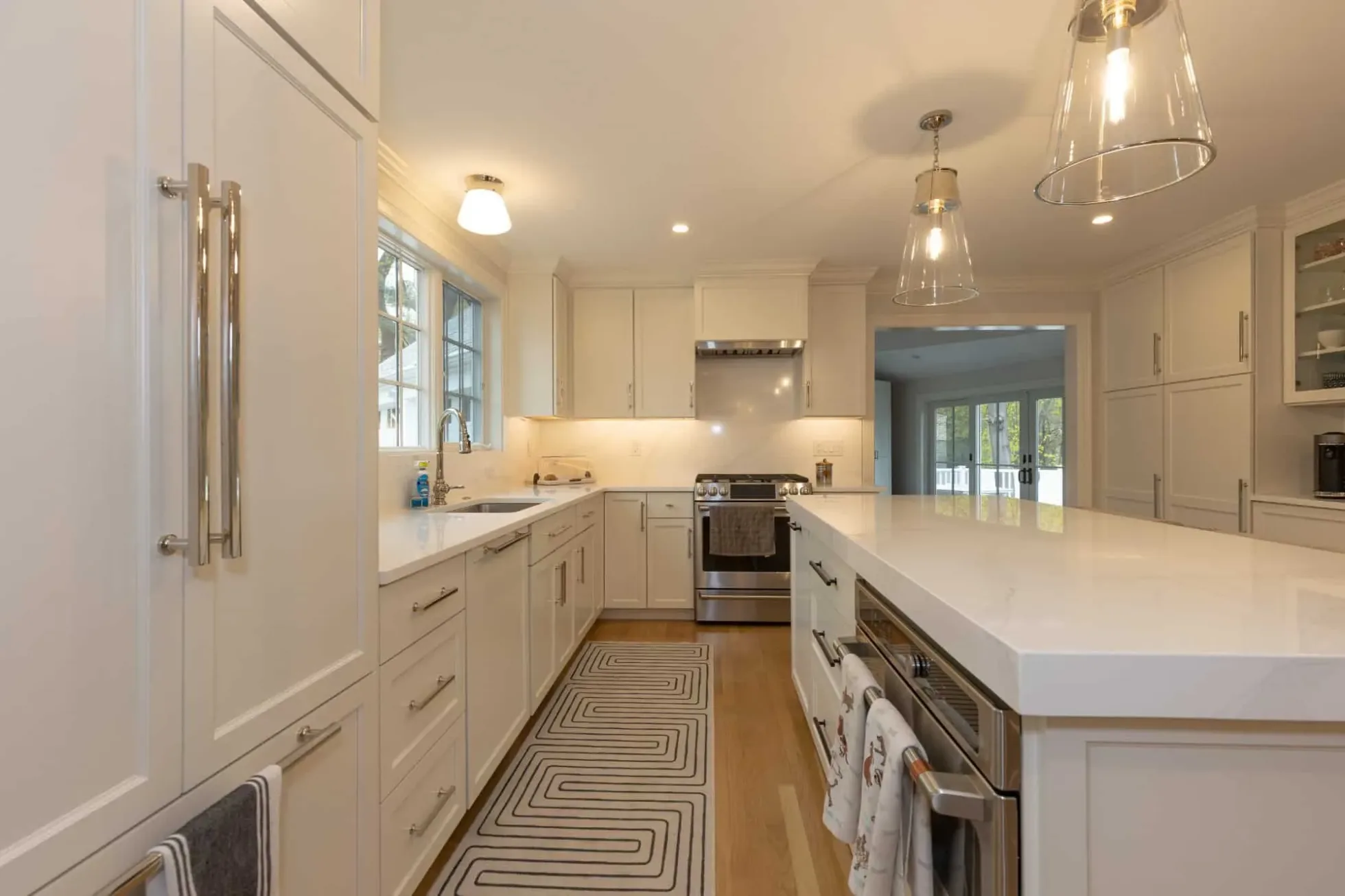 Kitchen run with quartz counters and backsplash, stainless appliances and a patterned runner