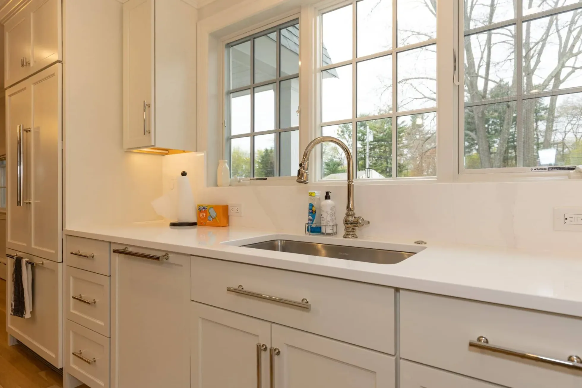 Kitchen counter and sink under large windows with under-cabinet lighting